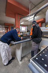 Image showing carpenters calculating and programming a cnc wood working machin