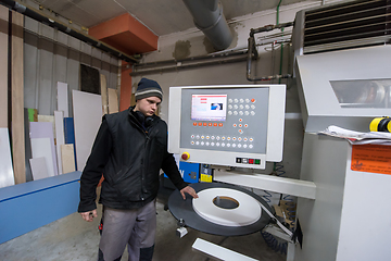 Image showing carpenter calculating and programming a cnc wood working machine