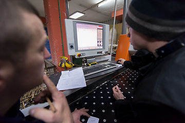 Image showing carpenters calculating and programming a cnc wood working machin