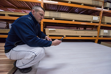 Image showing carpenter using a mobile phone to calculate measures