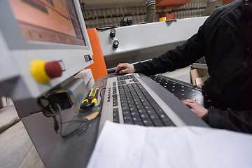 Image showing carpenters calculating and programming a cnc wood working machin