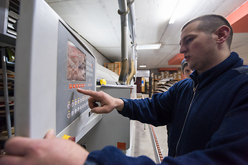 Image showing carpenter calculating and programming a cnc wood working machine