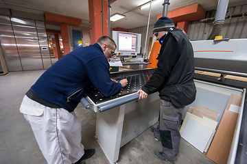 Image showing carpenters calculating and programming a cnc wood working machin