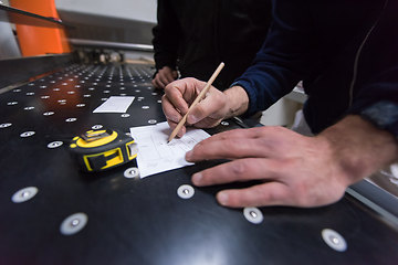 Image showing carpenters calculating and programming a cnc wood working machin