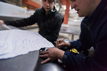 Image showing carpenters calculating and programming a cnc wood working machin