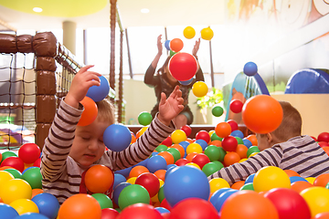 Image showing young mom playing with kids in pool with colorful balls