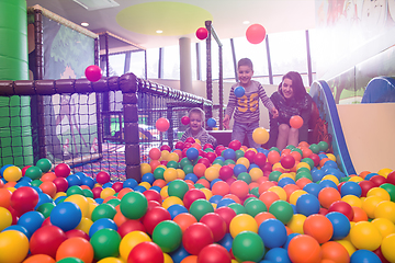 Image showing young mom playing with kids in pool with colorful balls