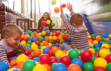 Image showing young mom playing with kids in pool with colorful balls