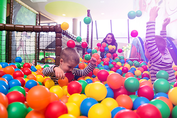 Image showing young mom playing with kids in pool with colorful balls