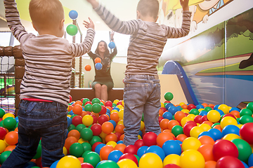 Image showing young mom playing with kids in pool with colorful balls