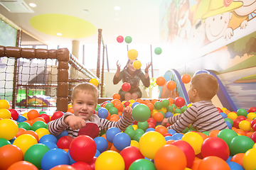 Image showing young mom playing with kids in pool with colorful balls