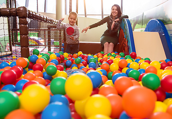 Image showing young mom playing with kids in pool with colorful balls