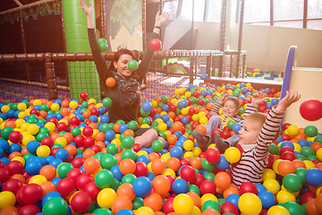 Image showing young mom playing with kids in pool with colorful balls