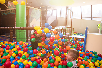 Image showing young mom playing with kids in pool with colorful balls