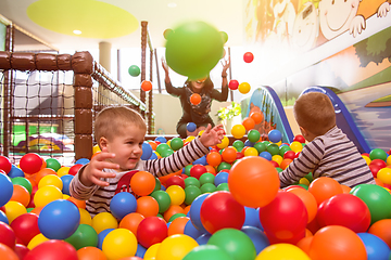 Image showing young mom playing with kids in pool with colorful balls