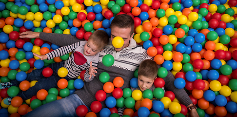 Image showing dad and kids playing in pool with colorful balls