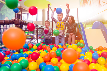 Image showing young mom playing with kids in pool with colorful balls