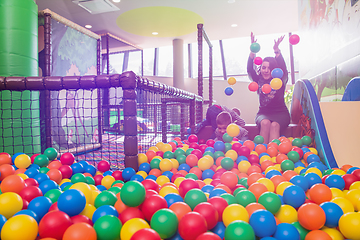 Image showing young mom playing with kids in pool with colorful balls