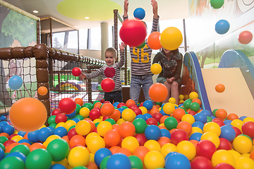 Image showing young mom playing with kids in pool with colorful balls