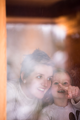 Image showing young mother and little cute daughter playing near the window