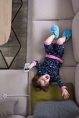 Image showing top view of little girl using a smartphone on the sofa