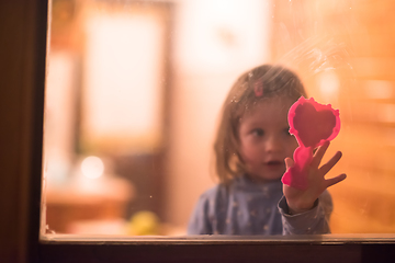 Image showing little cute girl playing near the window