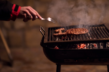 Image showing young man cooking meat on barbecue