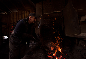 Image showing young traditional Blacksmith working with open fire