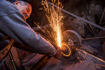 Image showing the blacksmith polishing metal products