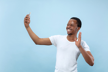 Image showing Half-length close up portrait of young man on blue background.