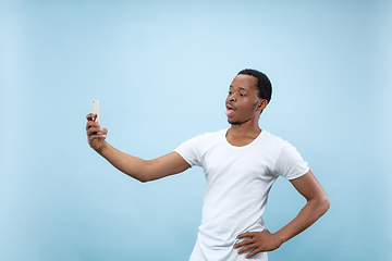 Image showing Half-length close up portrait of young man on blue background.