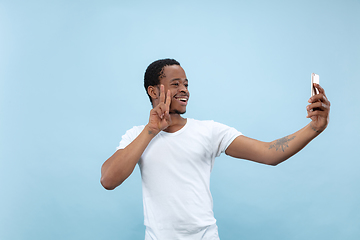 Image showing Half-length close up portrait of young man on blue background.