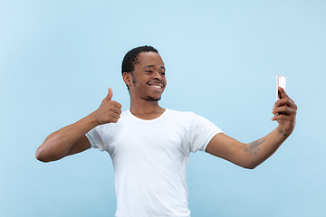 Image showing Half-length close up portrait of young man on blue background.