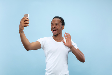 Image showing Half-length close up portrait of young man on blue background.