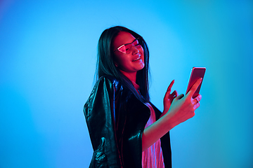 Image showing Beautiful girl\'s facial expression in neon light on blue studio background