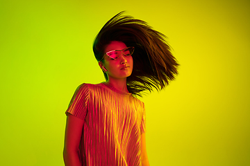 Image showing Beautiful girl\'s facial expression in neon light on yellow studio background