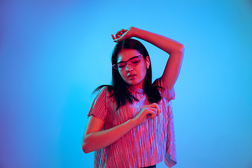 Image showing Beautiful girl\'s facial expression in neon light on blue studio background