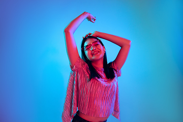 Image showing Beautiful girl\'s facial expression in neon light on blue studio background