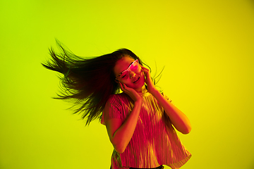 Image showing Beautiful girl\'s facial expression in neon light on yellow studio background