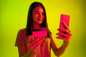 Image showing Beautiful girl\'s facial expression in neon light on yellow studio background