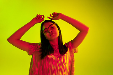 Image showing Beautiful girl\'s facial expression in neon light on yellow studio background