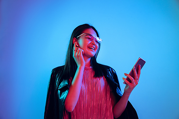 Image showing Beautiful girl\'s facial expression in neon light on blue studio background