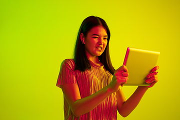 Image showing Beautiful girl\'s facial expression in neon light on yellow studio background