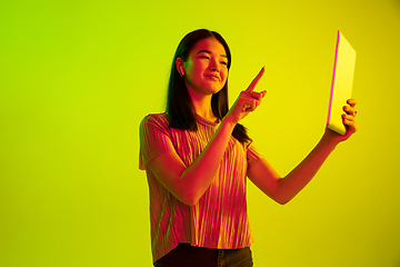 Image showing Beautiful girl\'s facial expression in neon light on yellow studio background