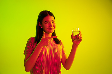 Image showing Beautiful girl\'s facial expression in neon light on yellow studio background