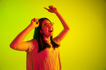 Image showing Beautiful girl\'s facial expression in neon light on yellow studio background