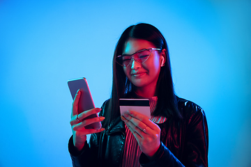 Image showing Beautiful girl\'s facial expression in neon light on blue studio background