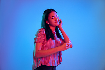 Image showing Beautiful girl\'s facial expression in neon light on blue studio background