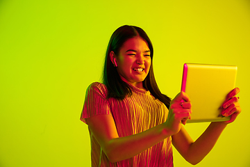 Image showing Beautiful girl\'s facial expression in neon light on yellow studio background