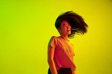 Image showing Beautiful girl\'s facial expression in neon light on yellow studio background